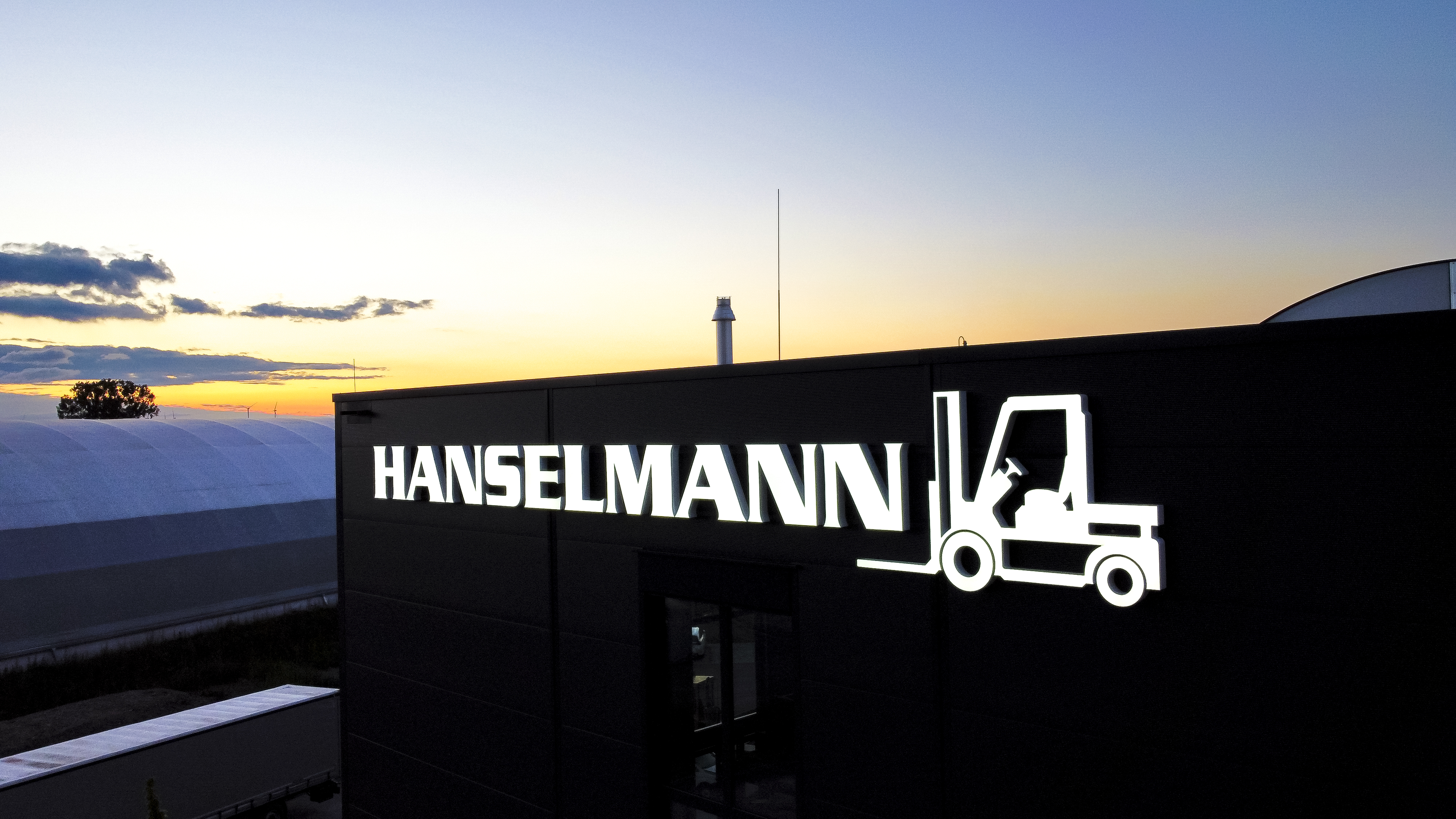 Firmengebäude am Abend mit beleuchtetem LED-Schriftzug "Hanselmann" in 6500K